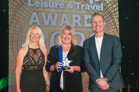 Sallyanne Gooch (left) from Potters Resorts presents the GLT award to Pamela Brooke on behalf of The Faulty Towers Dining Experience, alongside host Paul Zerdin.