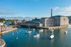 Boats and paddle boarders in the water next to the Royal William Yard in Portsmouth